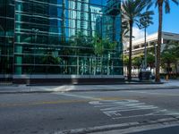 the street sign is at the end of the empty road where the tall buildings are reflected in the glass of the building