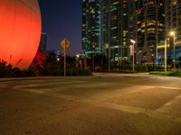 a photo of a large orange balloon and other lights on buildings in a city at night