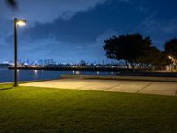 a lighted park bench is next to a street light and a grassy area at night