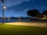 a lighted park bench is next to a street light and a grassy area at night