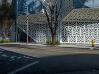 a yellow fire hydrant sitting next to a street under a building with lattices