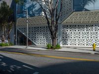 a yellow fire hydrant sitting next to a street under a building with lattices