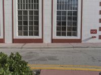 a yellow fire hydrant sits in front of two windows on the side of a brick building