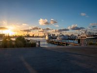 there are many boats docked at the pier in this photo the sun sets over the city