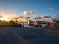 there are many boats docked at the pier in this photo the sun sets over the city