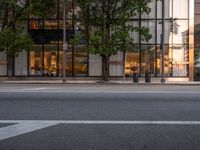 the view of an empty street with traffic lights reflected in the windows of the building