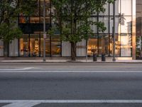 the view of an empty street with traffic lights reflected in the windows of the building