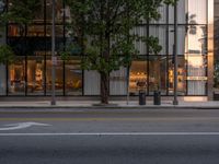 the view of an empty street with traffic lights reflected in the windows of the building