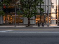 the view of an empty street with traffic lights reflected in the windows of the building