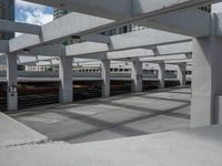 a train station with cars parked under a bridge and white structure overpassing it