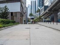 an empty sidewalk in a city with the buildings visible in the background - - - - -