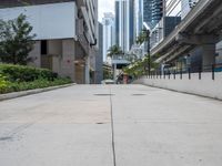 an empty sidewalk in a city with the buildings visible in the background - - - - -