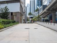 an empty sidewalk in a city with the buildings visible in the background - - - - -