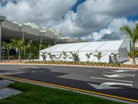 a building with a large tent at the front entrance and lawns on both sides