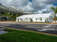 a building with a large tent at the front entrance and lawns on both sides