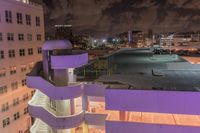 a purple building with some stairs and a clock tower on top of it at night