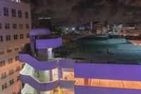 a purple building with some stairs and a clock tower on top of it at night