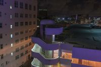 a purple building with some stairs and a clock tower on top of it at night