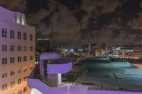 a purple building with some stairs and a clock tower on top of it at night