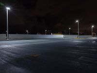 an empty parking lot lit with street lights on a cloudy night time day at twilight