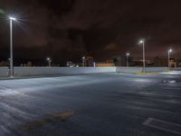 an empty parking lot lit with street lights on a cloudy night time day at twilight