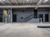 the entrance to an industrial building with open doors and an emergency door behind it and stairs leading up