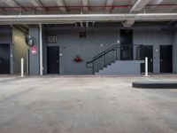 the entrance to an industrial building with open doors and an emergency door behind it and stairs leading up