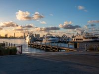 many boats are parked near a dock and buildings at sunset on the background with a bright sky