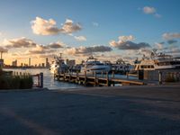 many boats are parked near a dock and buildings at sunset on the background with a bright sky