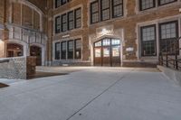 a person doing skateboard tricks off a stair way in a school building that's brick with two doors