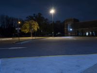 street lights shine brightly in front of an empty parking lot at nighttime with a clock tower visible