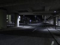 a long shot of an empty street underpass at night time with no light on