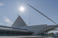 a white architectural structure with some people walking on it's way and some tall wires