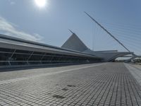 a man walking on the sidewalk with his luggage outside of a building with a tall triangular shaped structure