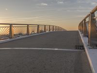 a skateboarder riding on a bridge at sunset with the sun setting behind him