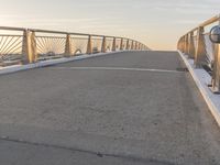 a skateboarder riding on a bridge at sunset with the sun setting behind him