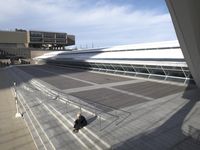 person walking up steps in front of building next to walkway and stairs with building in background