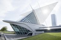 a large glass building that has a grass area on the sidewalk, and a person walking in front