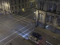 an aerial view of a street and cars driving down the road at night in the city