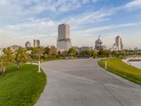 a large concrete pathway in a park leading to several tall buildings with trees on either side of it