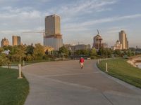 a large concrete pathway in a park leading to several tall buildings with trees on either side of it