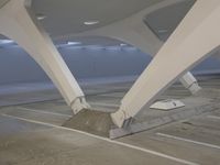 a man rides a skateboard while leaning against a wall in a parking garage under a slant roof