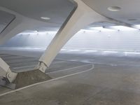 a man rides a skateboard while leaning against a wall in a parking garage under a slant roof