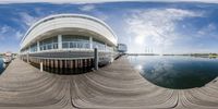 a fish eye lens is shown showing the building and water and clouds reflecting it in a body of water