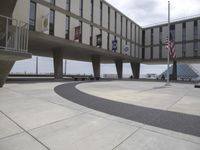 the floor of an empty area in front of a building and flags are hanging from it