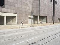 a man riding a skateboard in front of a large building with parking spaces underneath