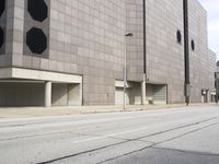 a man riding a skateboard in front of a large building with parking spaces underneath