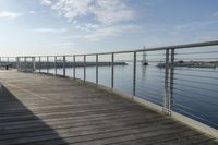 a boat is floating near a dock on a calm ocean day with a bench at the end of the walkway