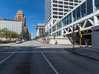 an empty street with two buildings in the background and cars driving on the road along the side