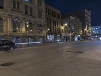 a night time view of city streets with buildings and a car driving at the same lane